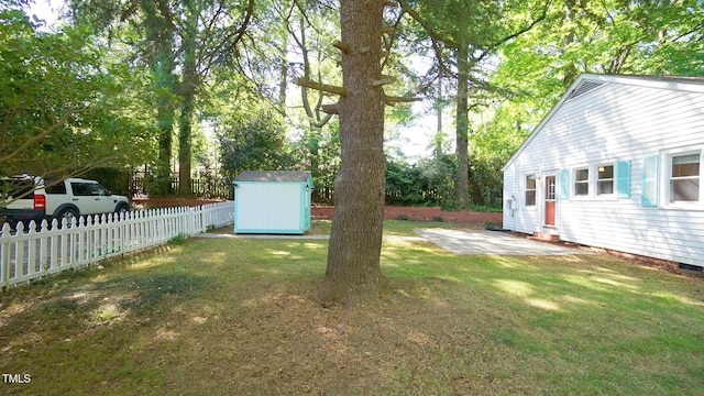 view of yard with a fenced backyard, a storage unit, an outdoor structure, and a patio