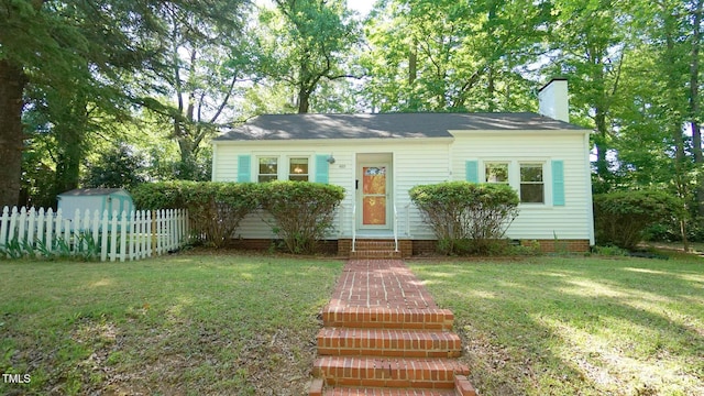view of front of home featuring fence, a front yard, entry steps, a chimney, and an outdoor structure