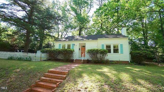 view of front of property with fence, a chimney, entry steps, and a front yard