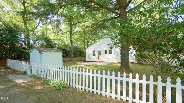 view of yard with an outdoor structure, a fenced front yard, and a storage unit