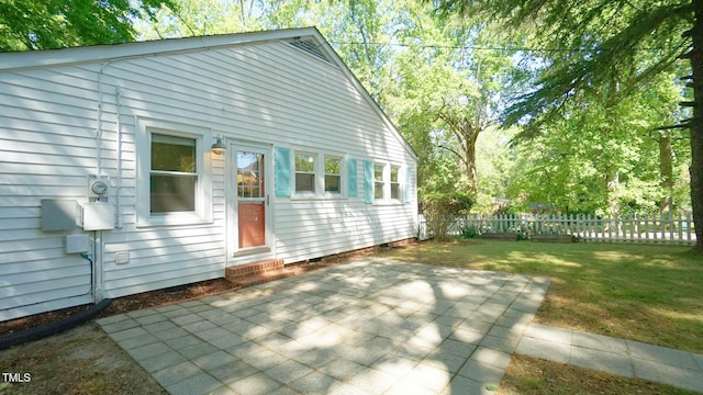 back of property featuring fence, crawl space, entry steps, a patio area, and a lawn