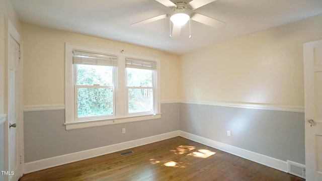 empty room featuring ceiling fan, plenty of natural light, wood finished floors, and visible vents