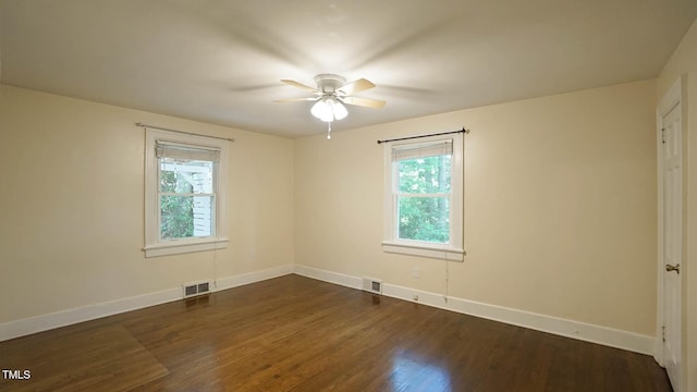 empty room featuring baseboards, ceiling fan, dark wood-type flooring, and visible vents