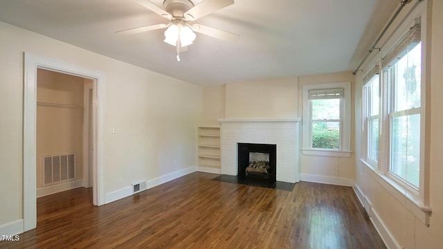 unfurnished living room featuring a fireplace, baseboards, visible vents, and dark wood-type flooring