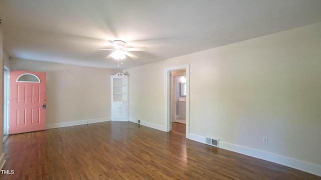 unfurnished room with dark wood-style flooring, ceiling fan, visible vents, and baseboards