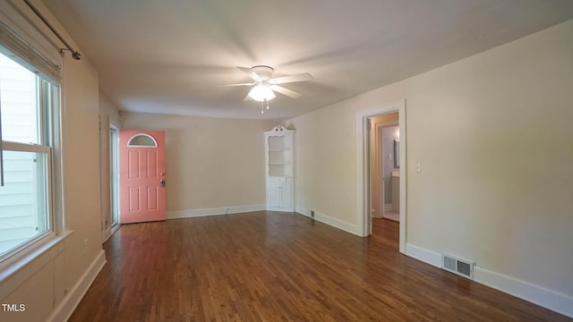 unfurnished room with plenty of natural light, a ceiling fan, dark wood-type flooring, and visible vents