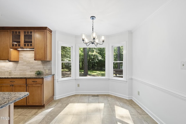 unfurnished dining area featuring crown molding, baseboards, an inviting chandelier, and light tile patterned floors