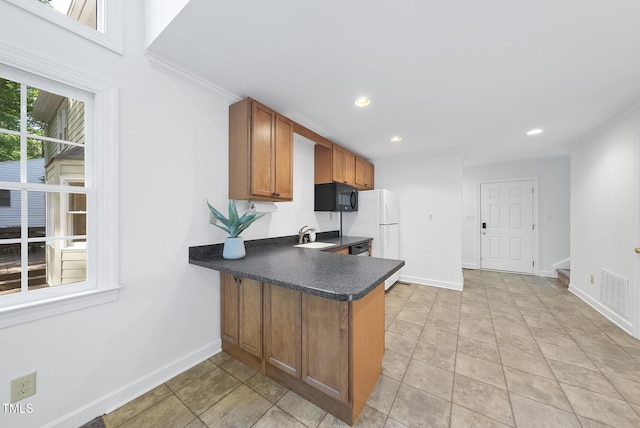 kitchen with brown cabinetry, black microwave, dark countertops, baseboards, and a peninsula