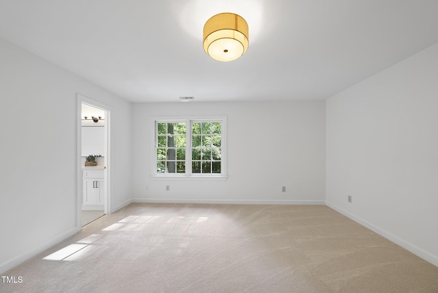 unfurnished room featuring light colored carpet, baseboards, and visible vents