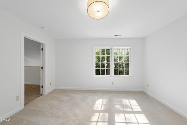 unfurnished bedroom with baseboards, visible vents, light carpet, and a spacious closet
