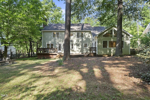 back of house with a chimney, fence, a yard, and a deck