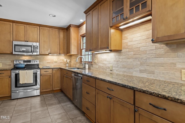 128 Cobblestone Dr, Chapel Hill, NC 27516 - kitchen featuring appliances with stainless steel finishes, brown cabinetry, tasteful backsplash, dark stone counters, and light tile patterned floors