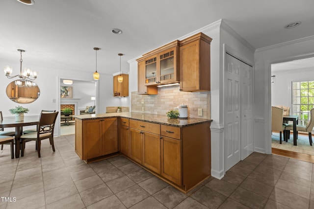 128 Cobblestone Dr, Chapel Hill, NC 27516 - kitchen with brown cabinetry, ornamental molding, tasteful backsplash, dark stone counters, and glass insert cabinets