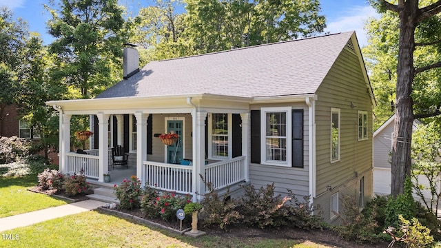 bungalow featuring covered porch, roof with shingles, a chimney, and a front yard