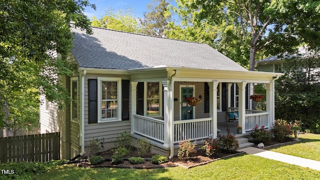 bungalow-style home featuring a porch, a shingled roof, a front lawn, and fence