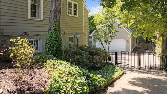view of side of property featuring driveway, fence, an outdoor structure, and a garage