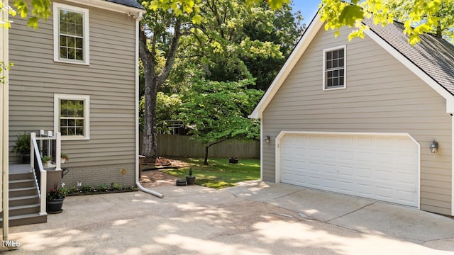 garage featuring concrete driveway and fence