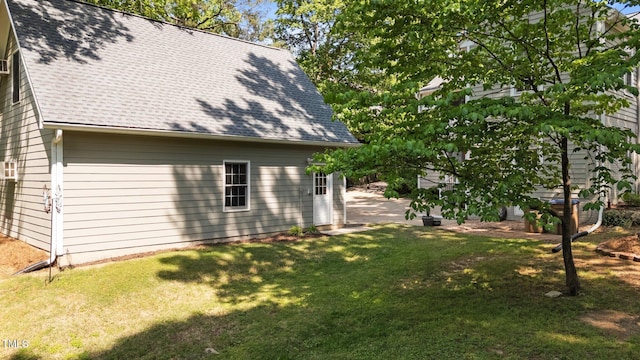 view of side of home with a lawn and roof with shingles