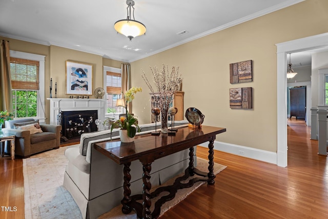 living area with crown molding, visible vents, and light wood-style flooring