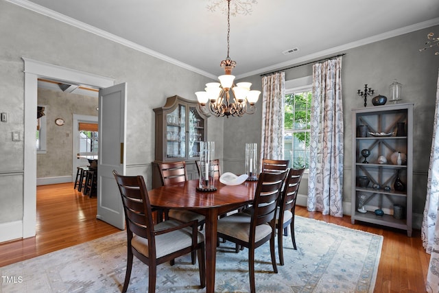 dining room featuring visible vents, crown molding, wood finished floors, and a chandelier