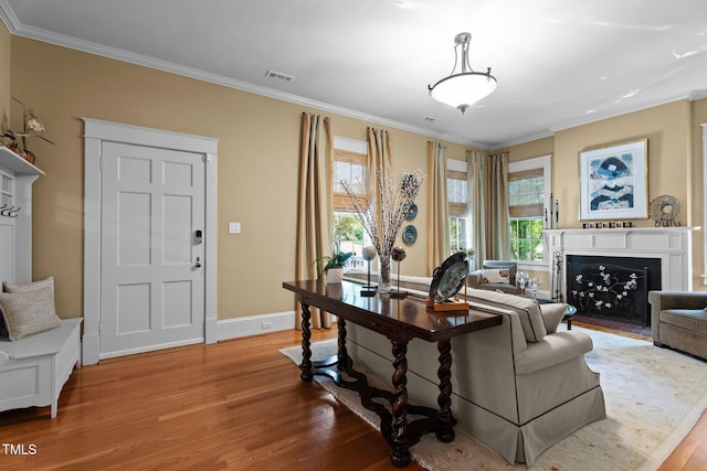living area featuring baseboards, a fireplace with flush hearth, ornamental molding, and wood finished floors