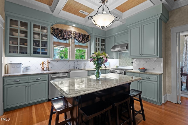 kitchen with appliances with stainless steel finishes, range hood, a sink, light wood finished floors, and coffered ceiling