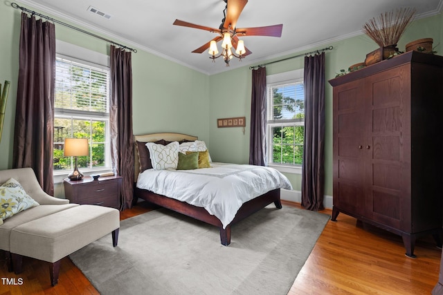 bedroom with visible vents, a ceiling fan, crown molding, and light wood-type flooring
