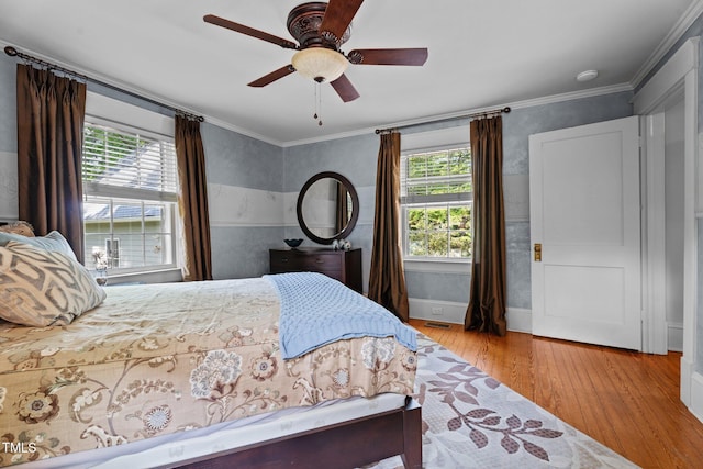 bedroom featuring visible vents, a ceiling fan, hardwood / wood-style floors, and multiple windows