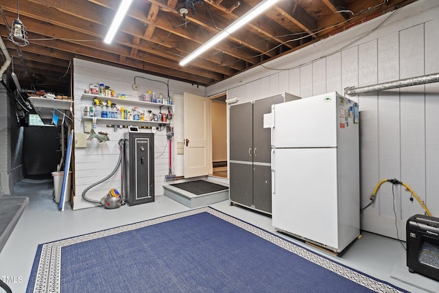 unfinished basement featuring freestanding refrigerator