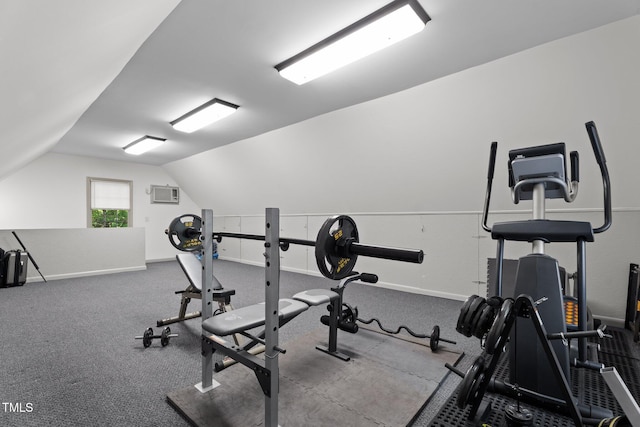 exercise room featuring baseboards, vaulted ceiling, and a wall unit AC