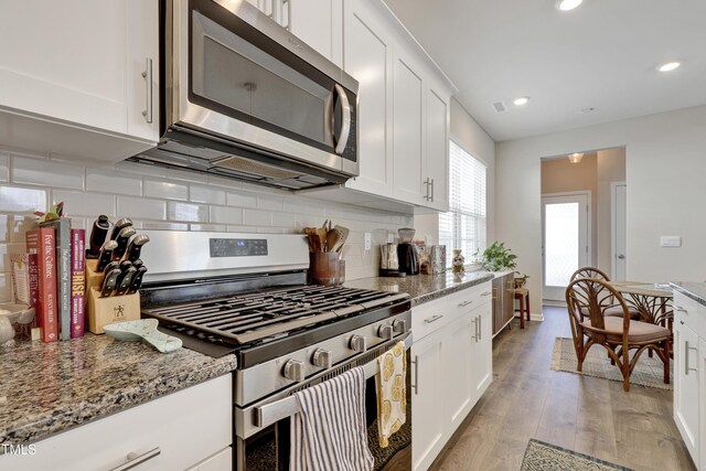 kitchen with appliances with stainless steel finishes, tasteful backsplash, light wood-type flooring, and white cabinets