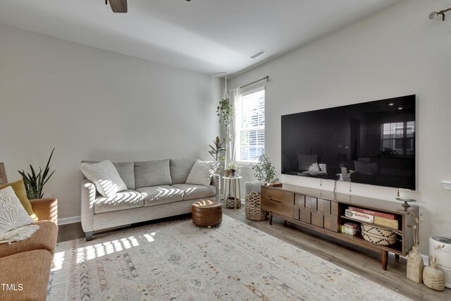 living area with a ceiling fan, wood finished floors, and visible vents