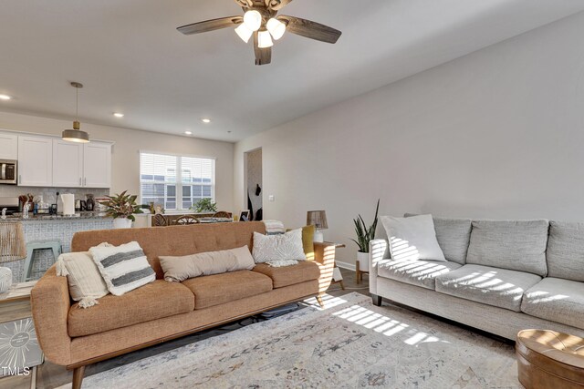 living area featuring baseboards, recessed lighting, ceiling fan, and wood finished floors