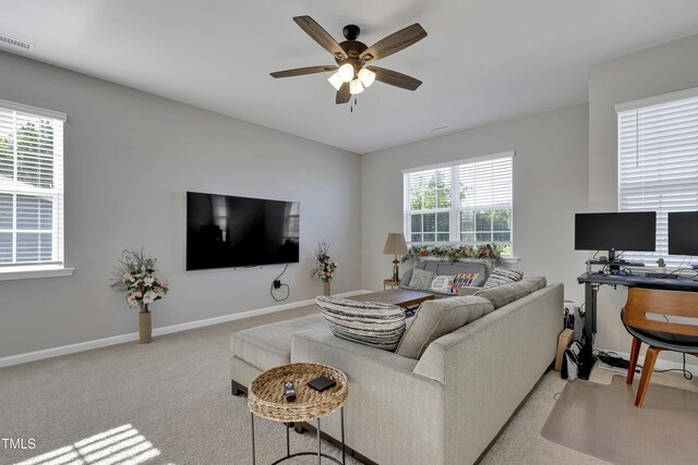 living area with baseboards, visible vents, a ceiling fan, and light colored carpet