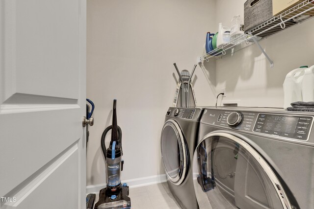 washroom featuring baseboards, light tile patterned floors, laundry area, and washer and clothes dryer