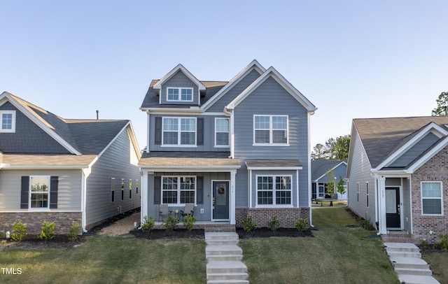 craftsman-style home with brick siding, a front lawn, and covered porch