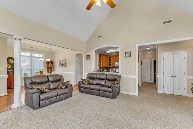 carpeted living room with visible vents, arched walkways, ceiling fan with notable chandelier, and high vaulted ceiling