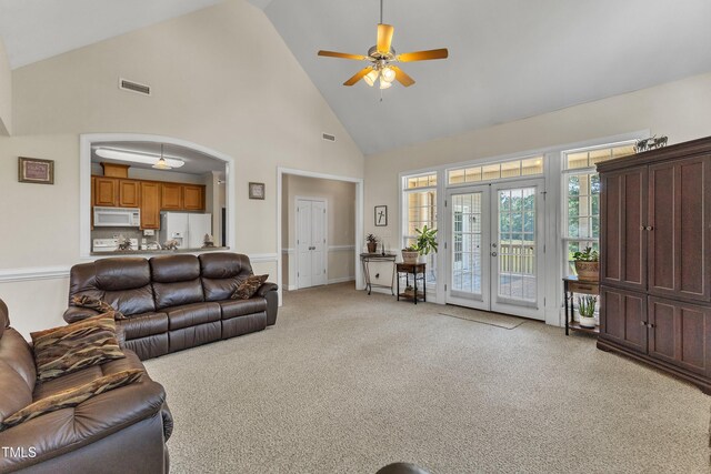 living area with french doors, a ceiling fan, visible vents, high vaulted ceiling, and light carpet
