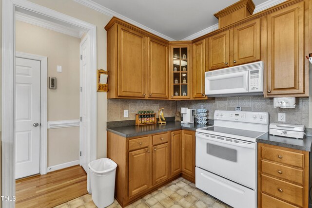 kitchen with dark countertops, decorative backsplash, brown cabinets, and white appliances