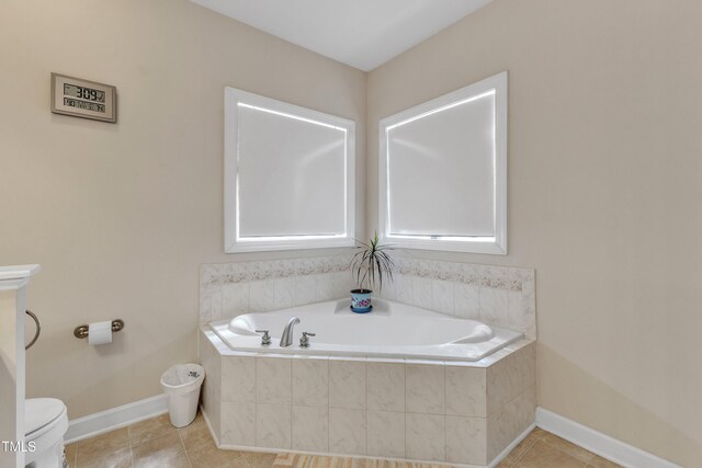 bathroom featuring tile patterned flooring, baseboards, a garden tub, and toilet