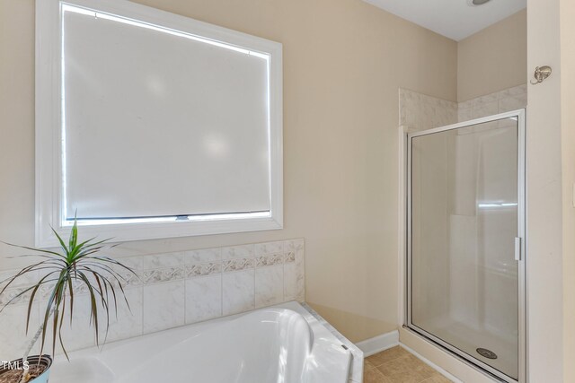 bathroom with baseboards, tile patterned flooring, a shower stall, and a bath