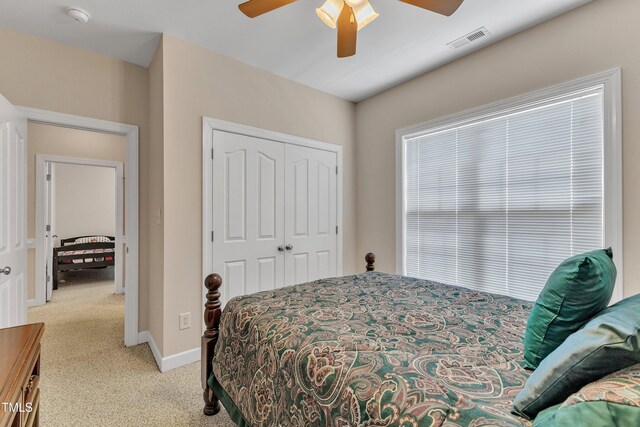 bedroom featuring visible vents, a closet, baseboards, light colored carpet, and a ceiling fan