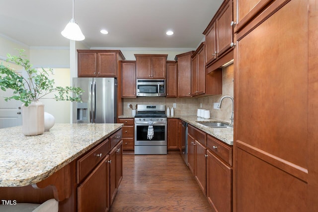 kitchen with crown molding, appliances with stainless steel finishes, light stone countertops, a sink, and dark wood-style floors