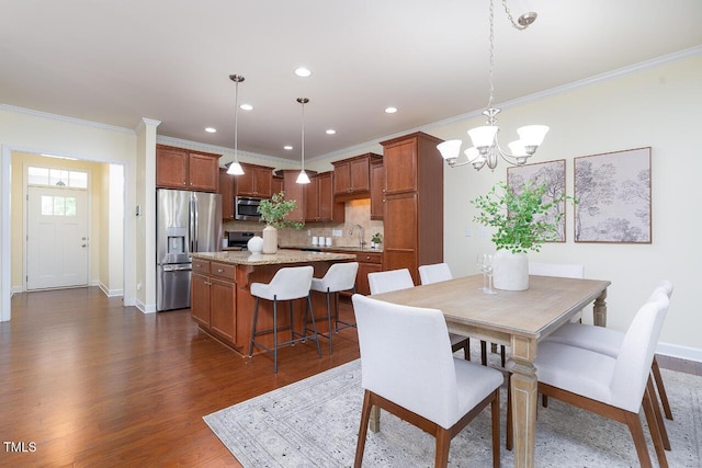 dining space featuring an inviting chandelier, ornamental molding, dark wood finished floors, and recessed lighting