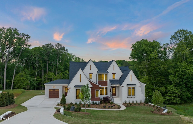 modern farmhouse with a garage, driveway, a front yard, and a standing seam roof