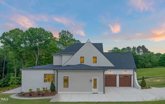 view of front of property with roof with shingles, an attached garage, driveway, and a front lawn