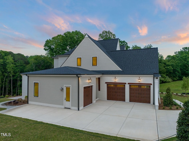 modern inspired farmhouse with an attached garage, driveway, and roof with shingles
