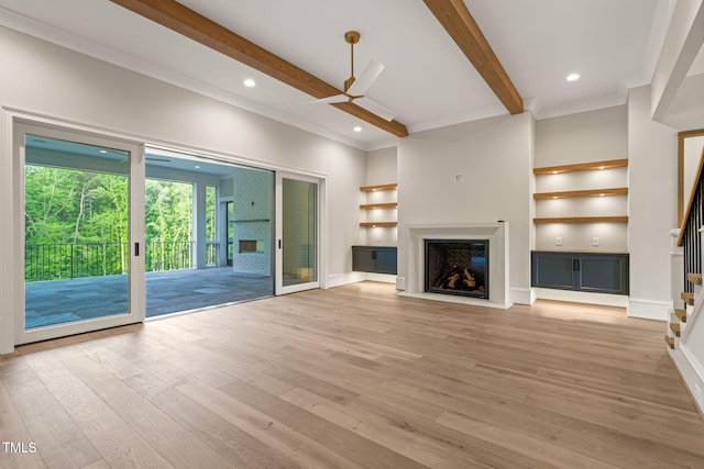 unfurnished living room with a fireplace with flush hearth, a ceiling fan, stairway, and beamed ceiling