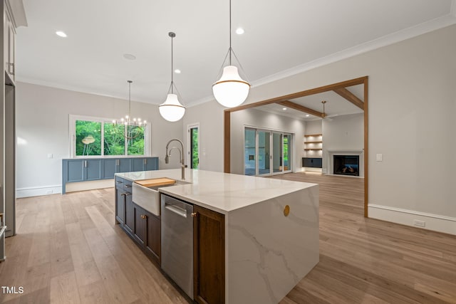 kitchen featuring a fireplace, dishwasher, a sink, light wood finished floors, and a chandelier
