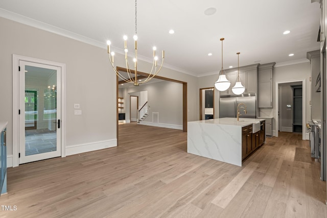 kitchen with crown molding, a sink, a kitchen island with sink, light wood-type flooring, and stainless steel built in refrigerator